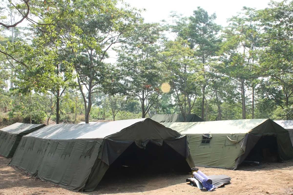 Deretan tenda regu berwarna hijau berdiri di camping ground UTC di bawah rimbun pepohonan.