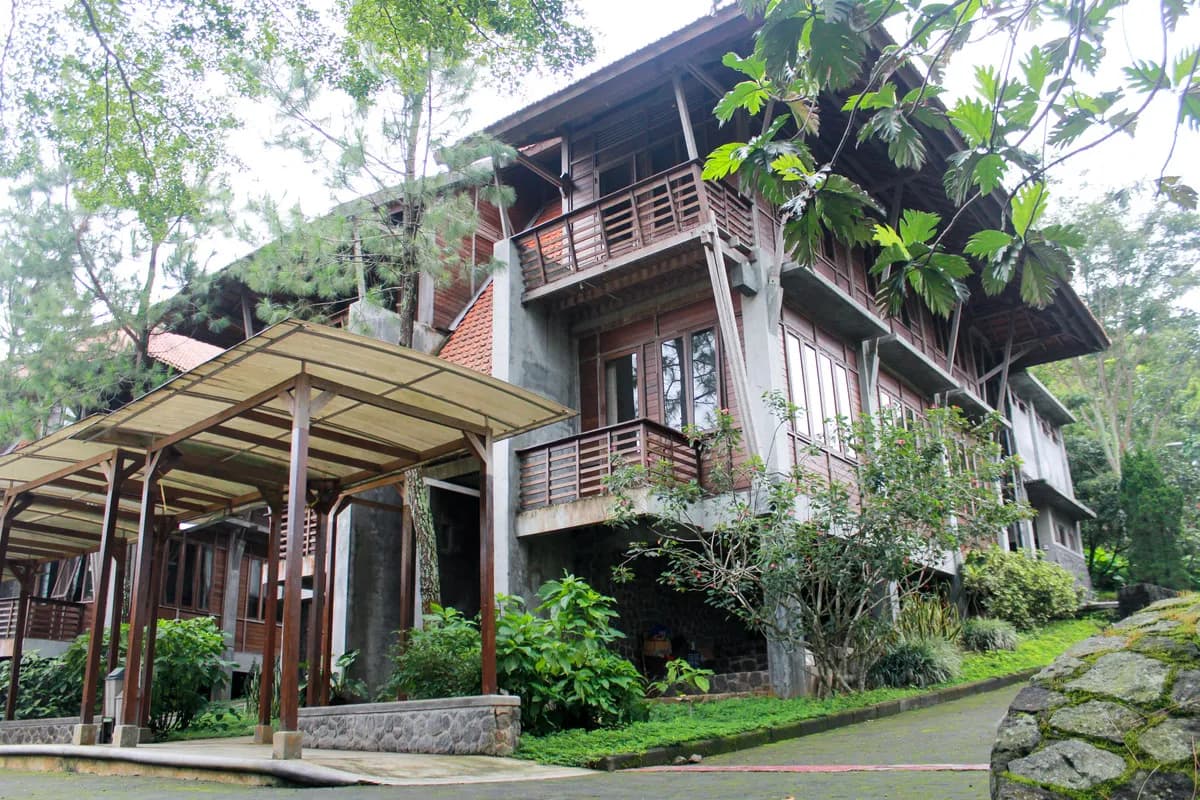 Cassava & Durian Cottage dilihat dari jalan kawasan, dengan koridor beratap di sisi kiri dan taman di sekitarnya.