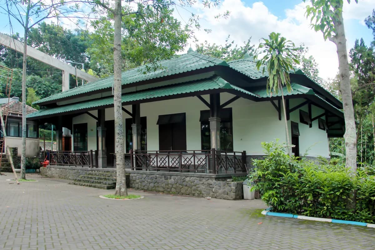 Bangunan Penanggungan Conference Room beratap genteng hijau dengan teras berpagar kayu dan halaman berpaving di depannya.